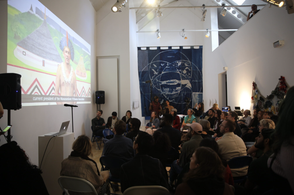 People sit looking at a screen in a gallery.