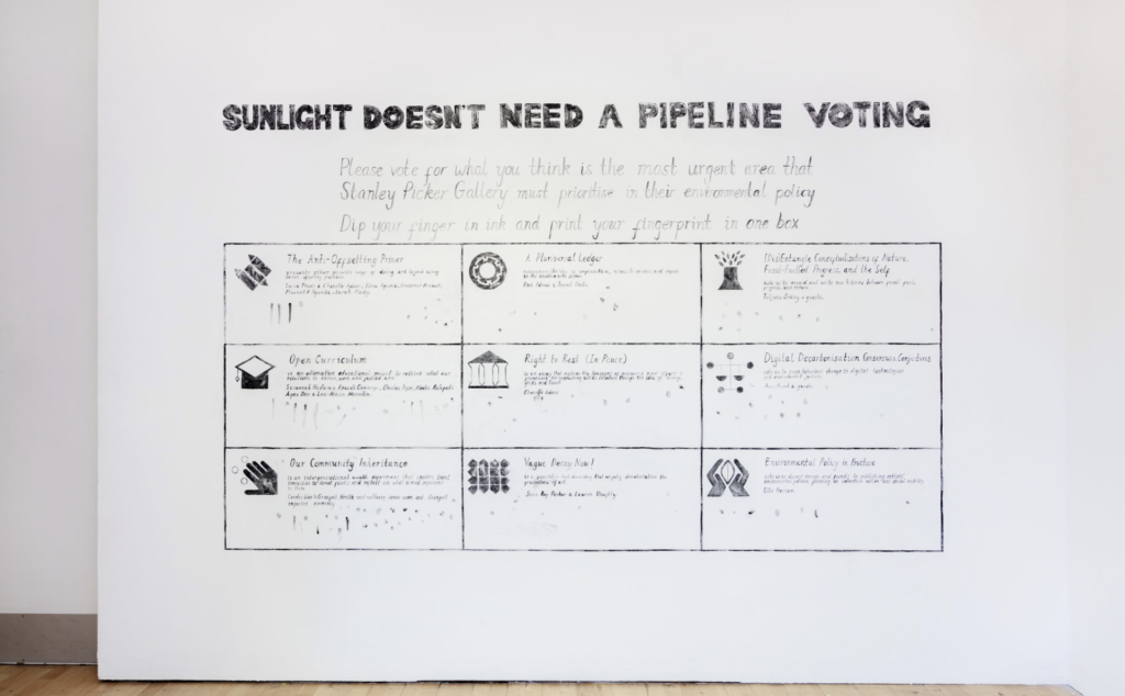 Sunlight Doesn't Need a Pipeline hand drawn on to a white wall in a gallery.